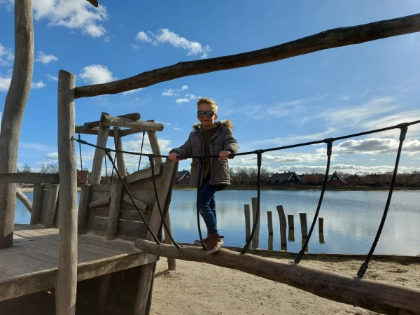 Kind loopt over touwbrug bij speelstrand vakantiepark Hof van Saksen