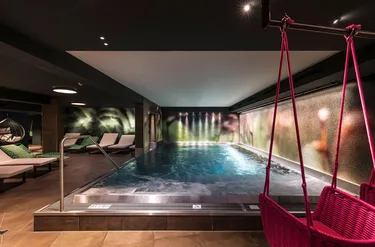 Zwembad met ligbedjes en een hangstoel