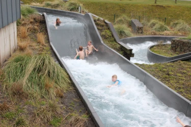 kinderen glijden van wildwaterbaan in de buitenlucht bij Hof Van Saksen