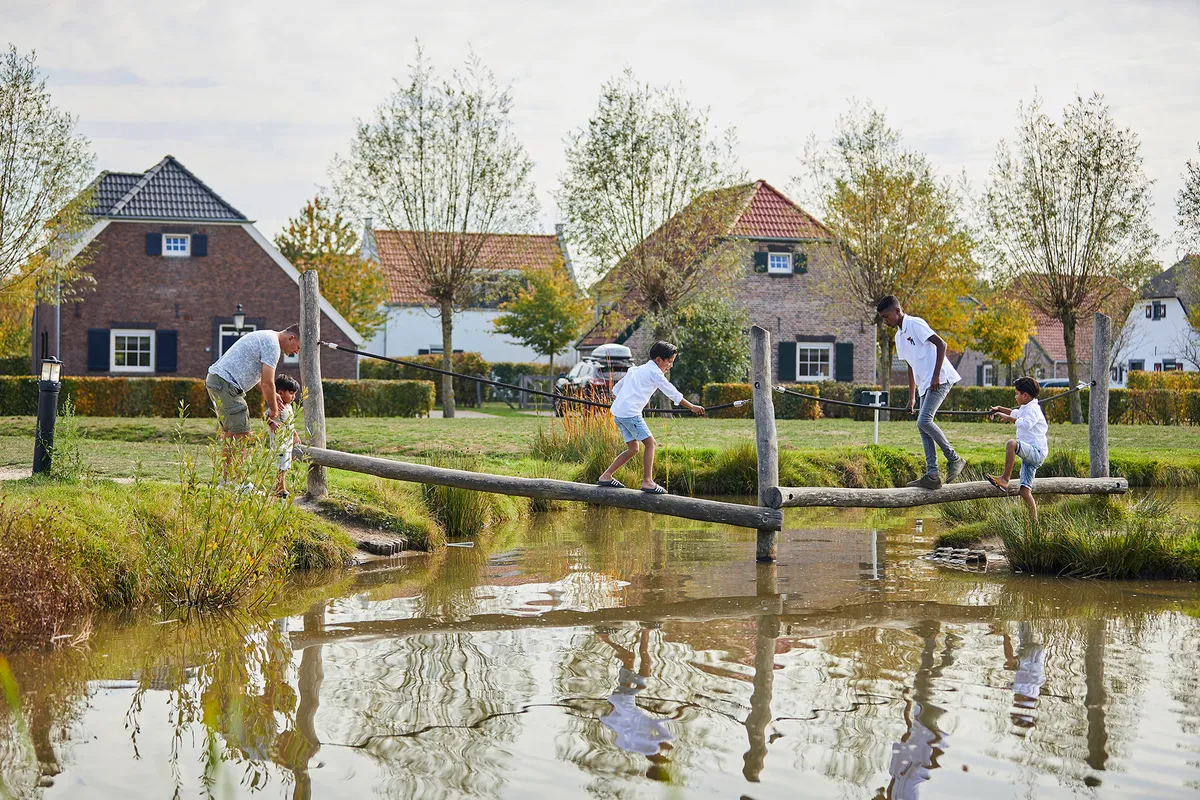 Kinderen lopen over houten balken in waterspeeltuin van De Leistert
