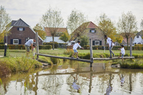 Kinderen lopen over houten balken in waterspeeltuin van De Leistert