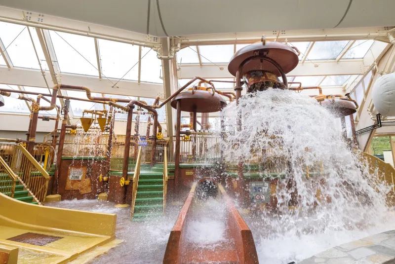 Het grote Water Playhouse in het zwemparadijs Aqua Mundo van Center Parcs De Huttenheugte, waarbij de reusachtige emmer met 900 liter water omkiept en voor een enorme plens zorgt over de glijbanen.