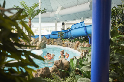 Gezin zwemt in de stroomversnelling voor een blauwe glijbaan bij vakantiepark de leistert