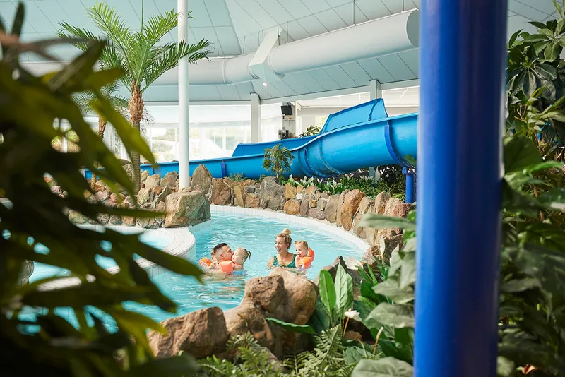Gezin zwemt in de stroomversnelling voor een blauwe glijbaan bij vakantiepark de leistert 