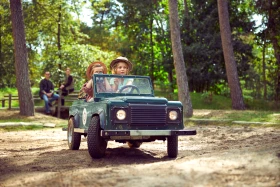 Twee kinderen rijden in een groene speelgoed-jeep over een bospad tijdens de Kids Safari bij Center Parcs De Kempervennen.