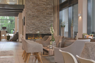 De sfeervolle lounge van Parkhotel Oberhausen met comfortabele stoelen en een gezellige open haard, ideaal voor families om te ontspannen.