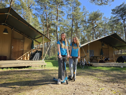 Twee meiden met een step voor de safaritenten op Landal Coldenhove, midden in de bossen van de Veluwe.