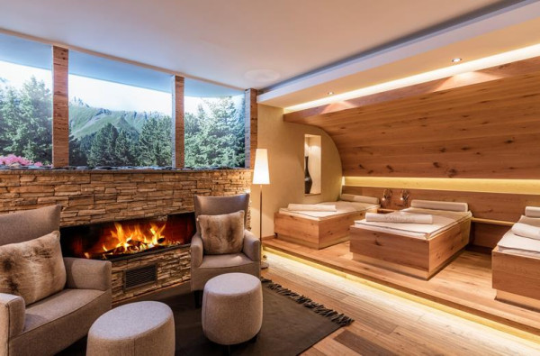 Wellnessruimte met verschillende ligbedjes en een zithoek met een hardvuur