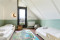 Sfeervolle kinderkamer op zolder in een vakantiehuis van Landal Drentse Lagune, met twee houten kinderbedden, een speelkleed en een maanlamp aan de muur.