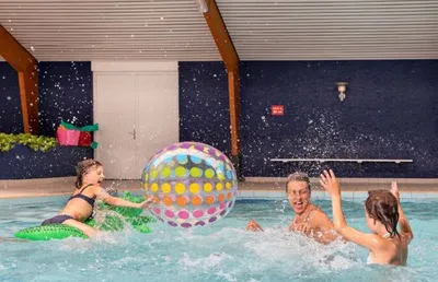 Kinderen spelen met een kleurrijke opblaasbal in een overdekt zwembad tijdens de meivakantie