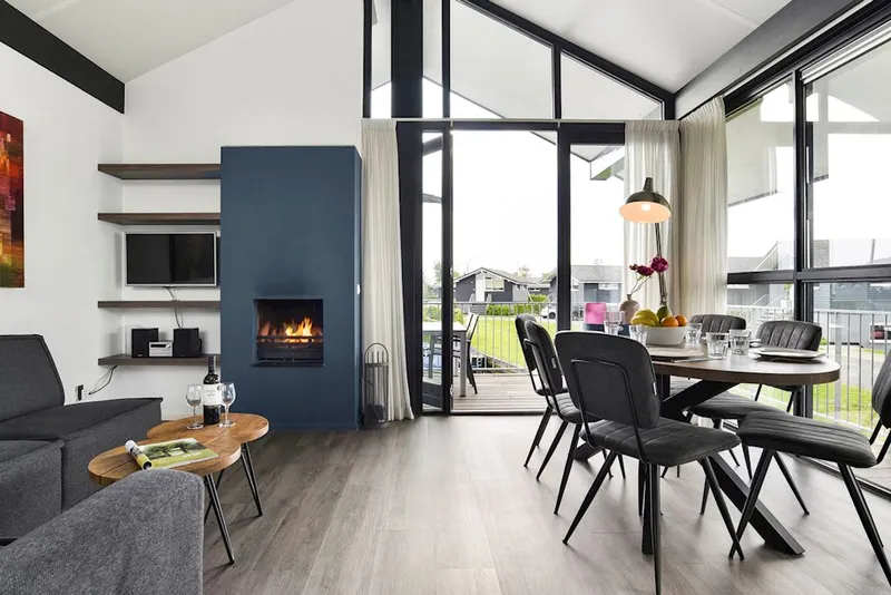 Luxe en moderne woonkamer met een gezellige, brandende sfeerhaard in een watervilla op Landal Sneekermeer, ideaal voor een herfstvakantie.