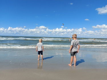 Twee kinderen staan aan de waterlijn op het strand in Nederland