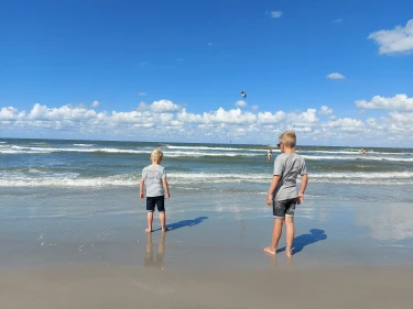 Twee kinderen staan aan de waterlijn op het strand in Nederland
