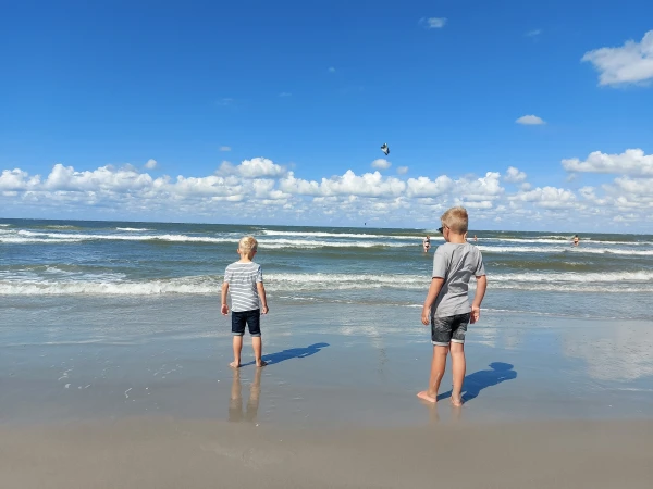 Twee kinderen staan aan de waterlijn op het strand in Nederland