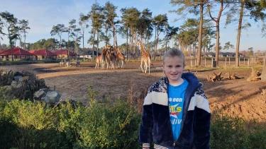 Kind poseert voor giraffen op Safari Resort Beekse Bergen