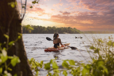 Vrouw in een kajak op het Victoriameer bij Beekse Bergen tijdens een prachtige zonsondergang