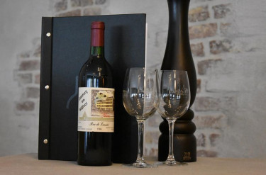 Een fles rode wijn met twee glazen en een menukaart in het restaurant van Hotel Atlanta voor een gastvrij en stijlvol verblijf