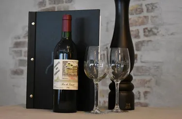 Een fles rode wijn met twee glazen en een menukaart in het restaurant van Hotel Atlanta voor een gastvrij en stijlvol verblijf