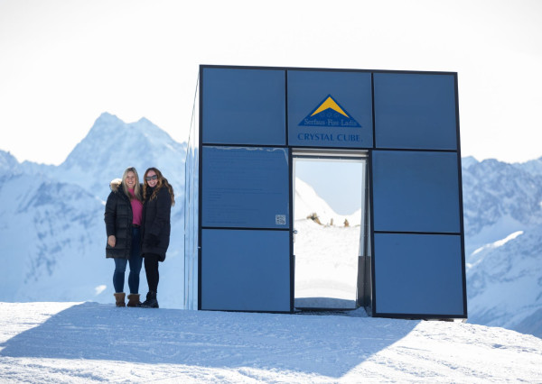 Vrouwen staan te poseren op de skipiste met uitzicht over het dal