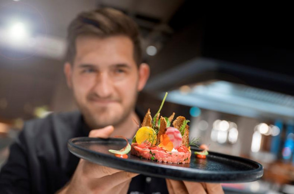 Een chef presenteert een culinair gerecht in het restaurant van ATLANTIC Hotel Münster