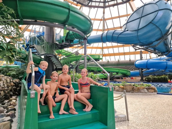 Kinderen zitten op de trap van een grote waterglijbaan bij landal De Lommerbergen. 
