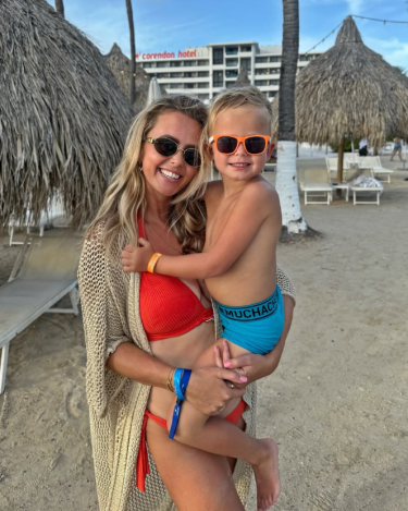 Moeder en kind met zonnebril op poseren in zwemkleding op een strand met strandbedjes