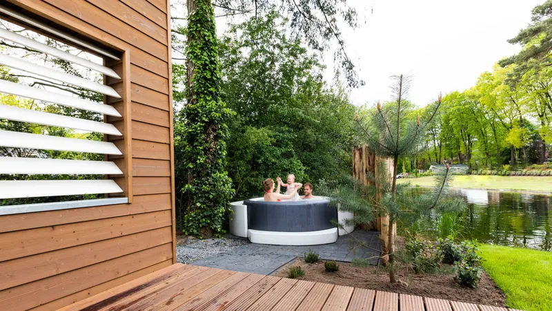 Gasten ontspannen in een privé hottub in de tuin van een wellness vakantiehuis, omgeven door de natuur van de Veluwe.