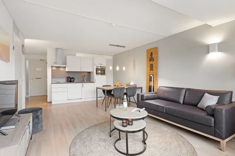 Stijlvolle en moderne woonkamer met open keuken in een appartement van Landal Ameland State, compleet met zithoek en eettafel.