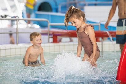 Twee jonge kinderen spelen en spetteren met water in het ondiepe peuterbad van het zwembad op Bungalowpark De Katjeskelder.