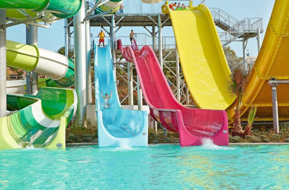 Kinderen racen van de drie steile, naast elkaar gelegen (blauw, roze, geel) waterglijbanen in het aquapark van Grecotel Club Marine Palace.
