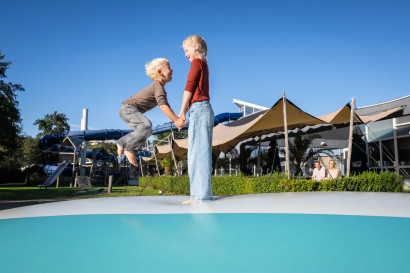 Twee kinderen springen hand in hand op de grote airtrampoline op Kustpark Texel.