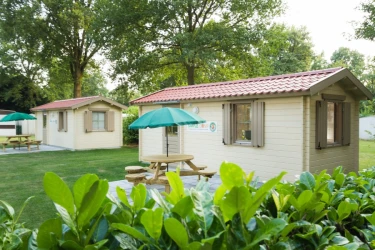 Een simpel chalet huisje met een picknick tafel en groene parasol.