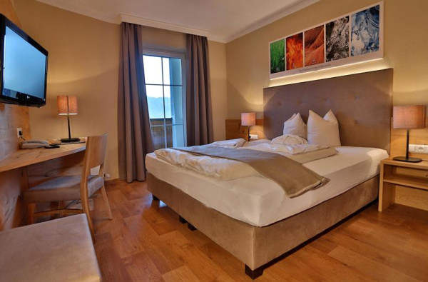 Hotelkamer met comfortabel tweepersoonsbed, nachtkastjes, moderne inrichting en zachte verlichting.