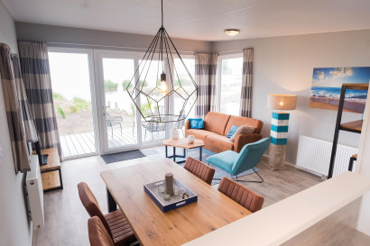 De stijlvolle en moderne woonkamer van een vakantiehuisje op Vakantiepark Bergumermeer met uitzicht naar buiten.