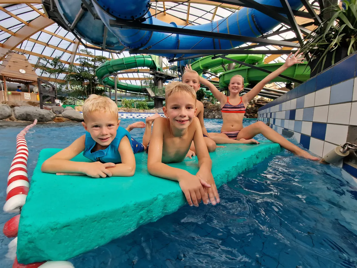 Kinderen drijven op een mat in het subtropisch zwembad van Landal De Lommerbergen.