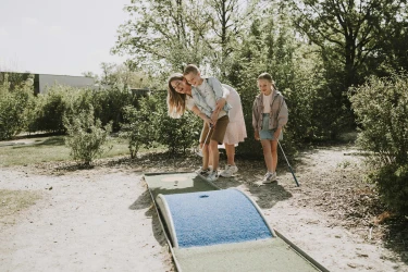 Gezin speelt minigolf op groene minigolfbaan in Vakantiepark Dierenbos