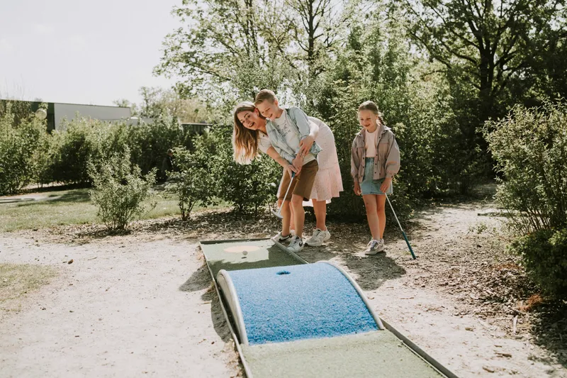 Gezin speelt minigolf op groene minigolfbaan in Vakantiepark Dierenbos