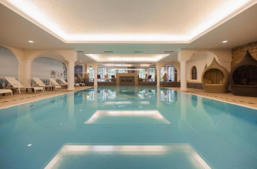 Groot blauw zwembad met ligbedjes en witte pilaren