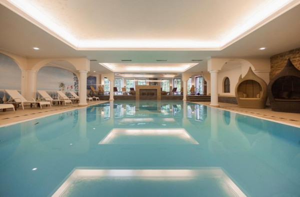 Groot blauw zwembad met ligbedjes en witte pilaren