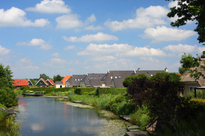 Overzicht van Vakantiepark Emslandermeer in Vlagtwedde, Groningen, met vakantiehuisjes gelegen aan het water onder een blauwe lucht.