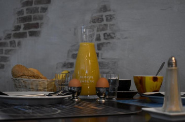 Uitgebreid ontbijt in Hotel Atlanta met een karaf verse jus d'orange gekookte eieren en broodjes tegen een sfeervolle bakstenen muur