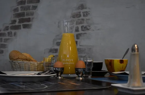 Uitgebreid ontbijt in Hotel Atlanta met een karaf verse jus d'orange gekookte eieren en broodjes tegen een sfeervolle bakstenen muur