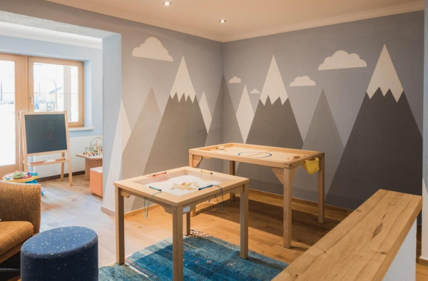 Speelkamer voor kinderen met speels behang en tafels met spelletjes