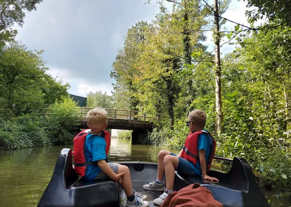 Kinderen zitten op bootje door de natuur bij Center Parcs