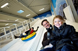 Een vader en dochter die plezier hebben met tubing van de indoor sneeuwhelling in Winter World, Lalandia.