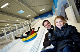 Een vader en dochter die plezier hebben met tubing van de indoor sneeuwhelling in Winter World, Lalandia.