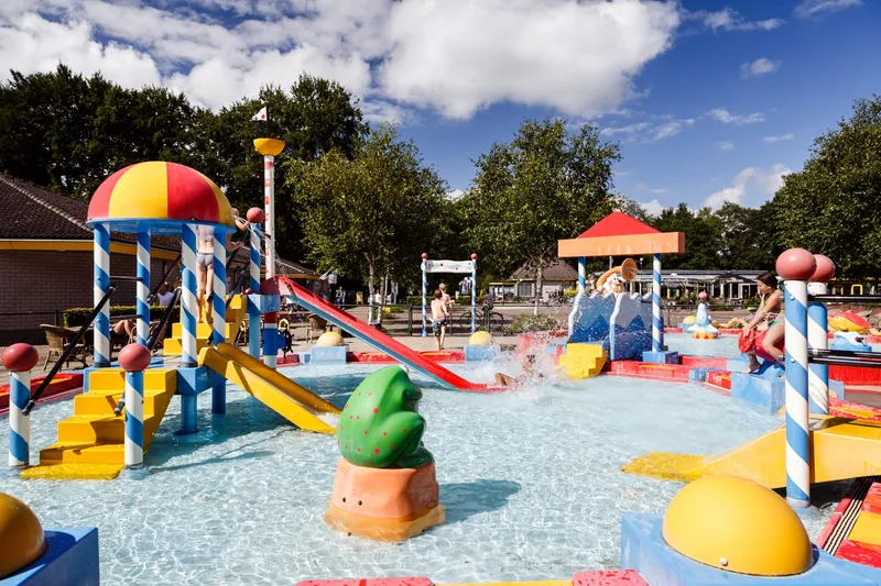 De kleurrijke waterspeeltuin (spraypark) van RCN de Roggeberg in Friesland, vol met glijbanen, sproeiers en speeltoestellen voor kinderen.