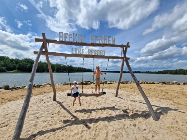 Kinderen schommelen op strand bij Beekse Bergen Lake Resort