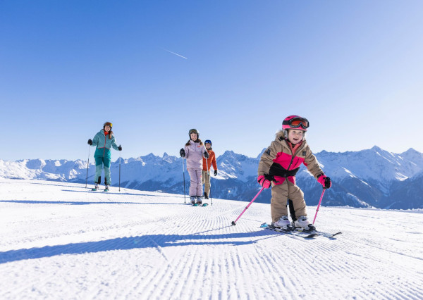 Gezin is aan het skiën op de piste met uitzicht over het dal