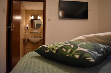 Hotelkamer in Hotel Atlanta met een groen bed en een open deur naar de en suite badkamer
